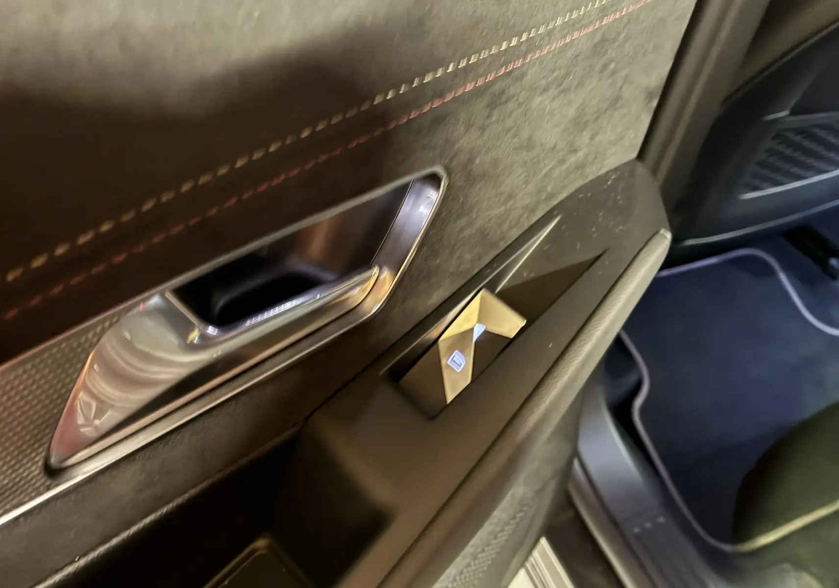 Détail de la porte intérieure côté gauche du DS7 E-TENSE 2024 gris, avec poignée chrome et bouton de lève-vitre.