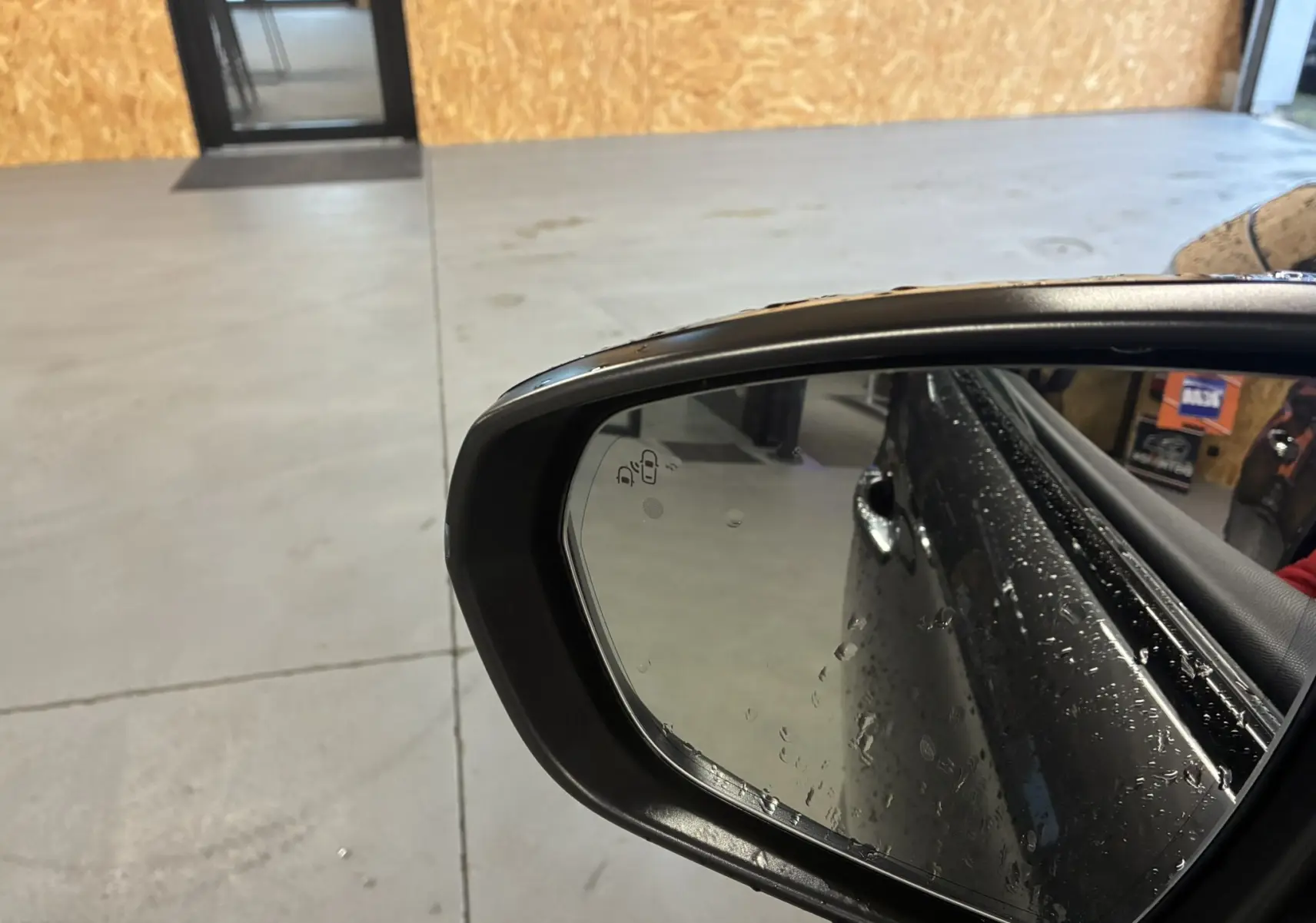 Rétroviseur côté droit du DS7 E-TENSE gris 2024 avec gouttes d'eau et reflet partiel de la porte arrière.