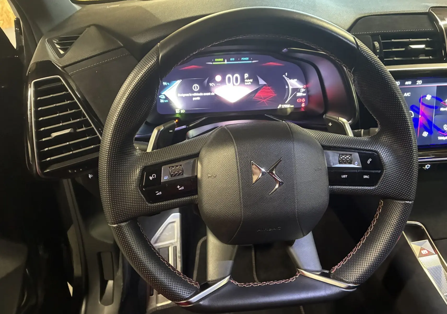 Vue rapprochée du volant noir texturé et du tableau de bord digital du DS7 E-TENSE 2024 gris hybride essence.