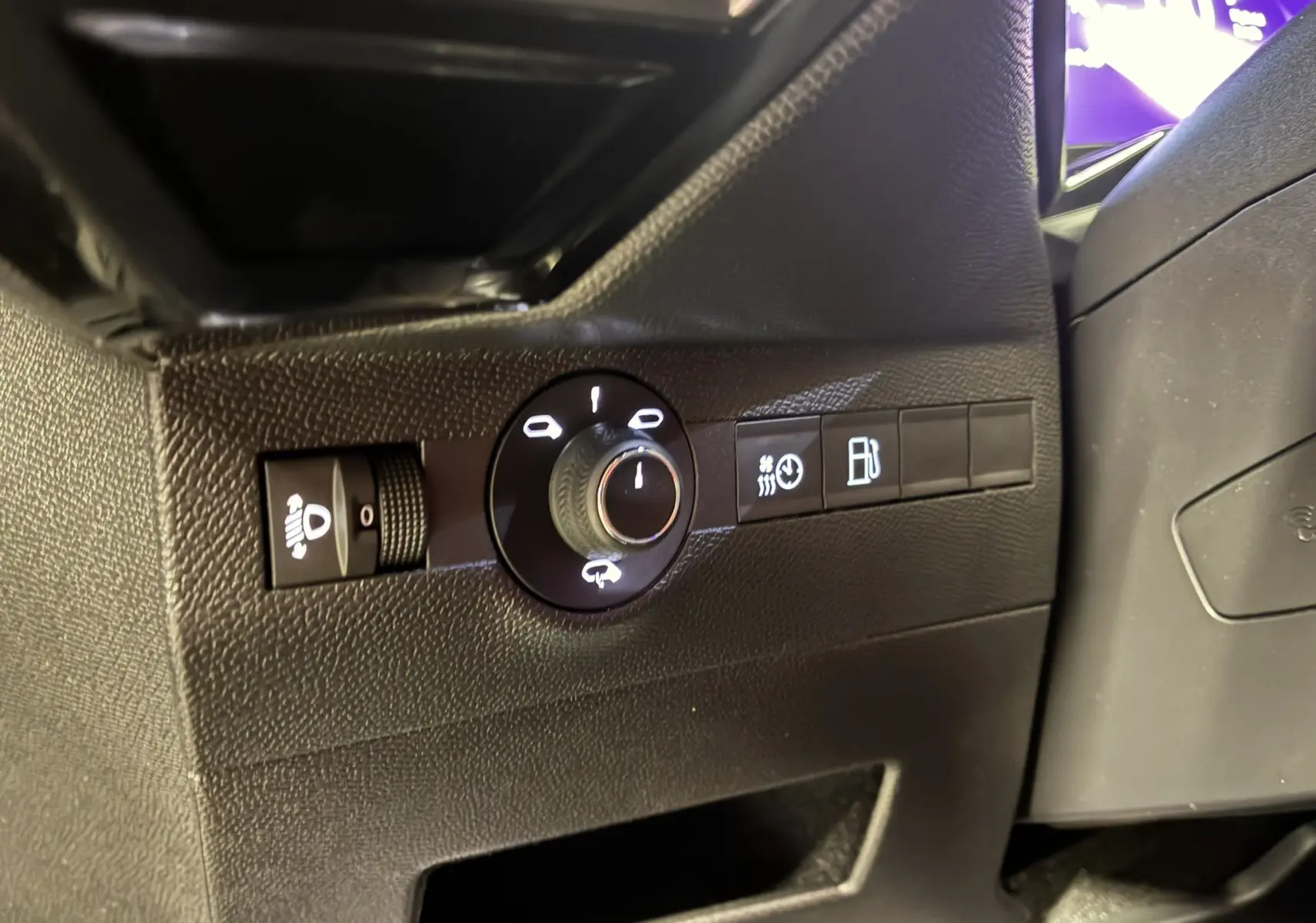 Gros plan sur les commandes d'éclairage et de carburant à gauche du volant dans l'habitacle noir du DS7 E-TENSE gris 2024.