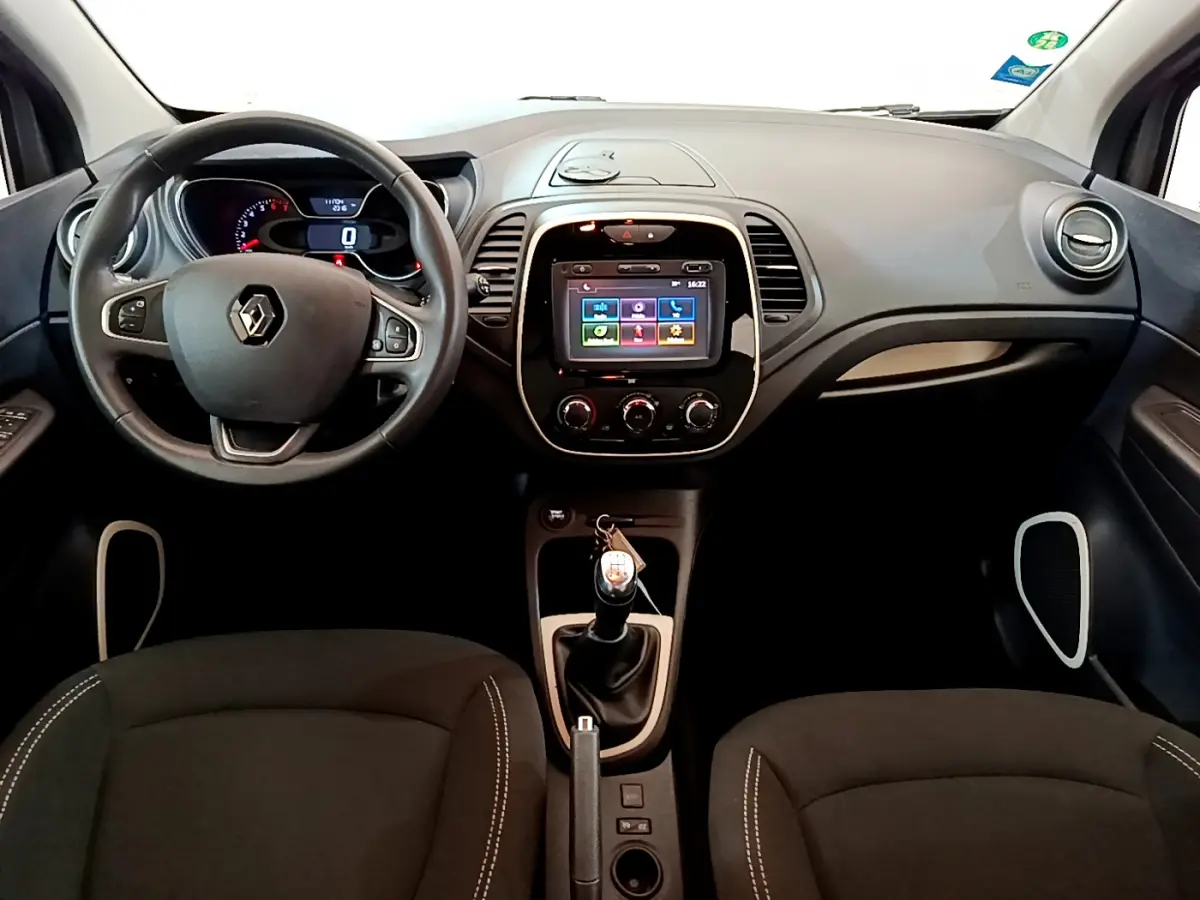 Vue intérieure frontale du tableau de bord gris foncé du Renault Captur avec volant cuir multifonctions et écran tactile central.