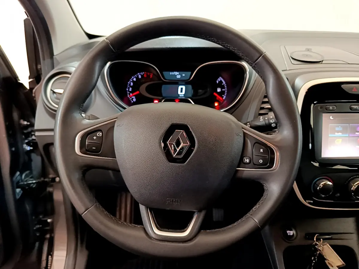 Vue rapprochée du volant cuir multifonctions du Renault Captur gris foncé avec tableau de bord et écran tactile.