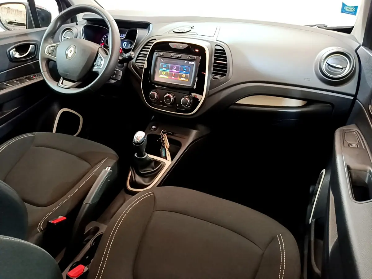 Vue intérieure côté conducteur du Renault Captur gris foncé, avec volant cuir multifonctions et écran tactile central.