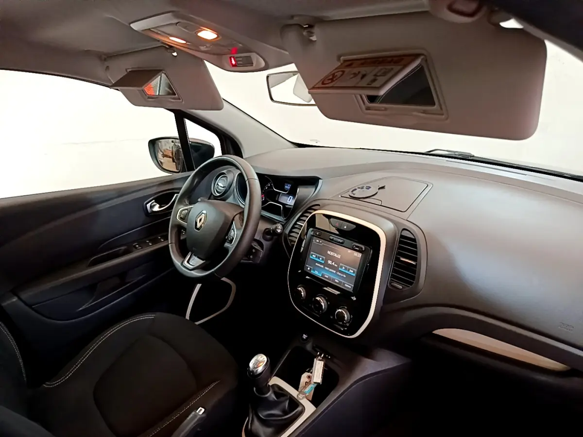 Vue intérieure côté conducteur du Renault Captur gris foncé, volant cuir multifonctions et écran tactile central allumé.