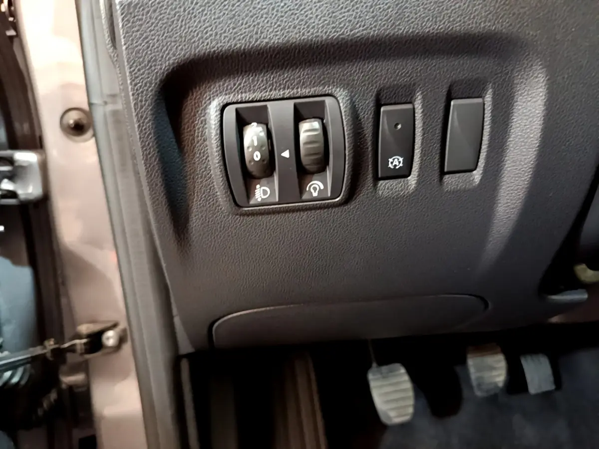 Détail des commandes de réglage des phares et bouton stop-start côté gauche du tableau de bord d’un Renault Captur gris foncé 2018.