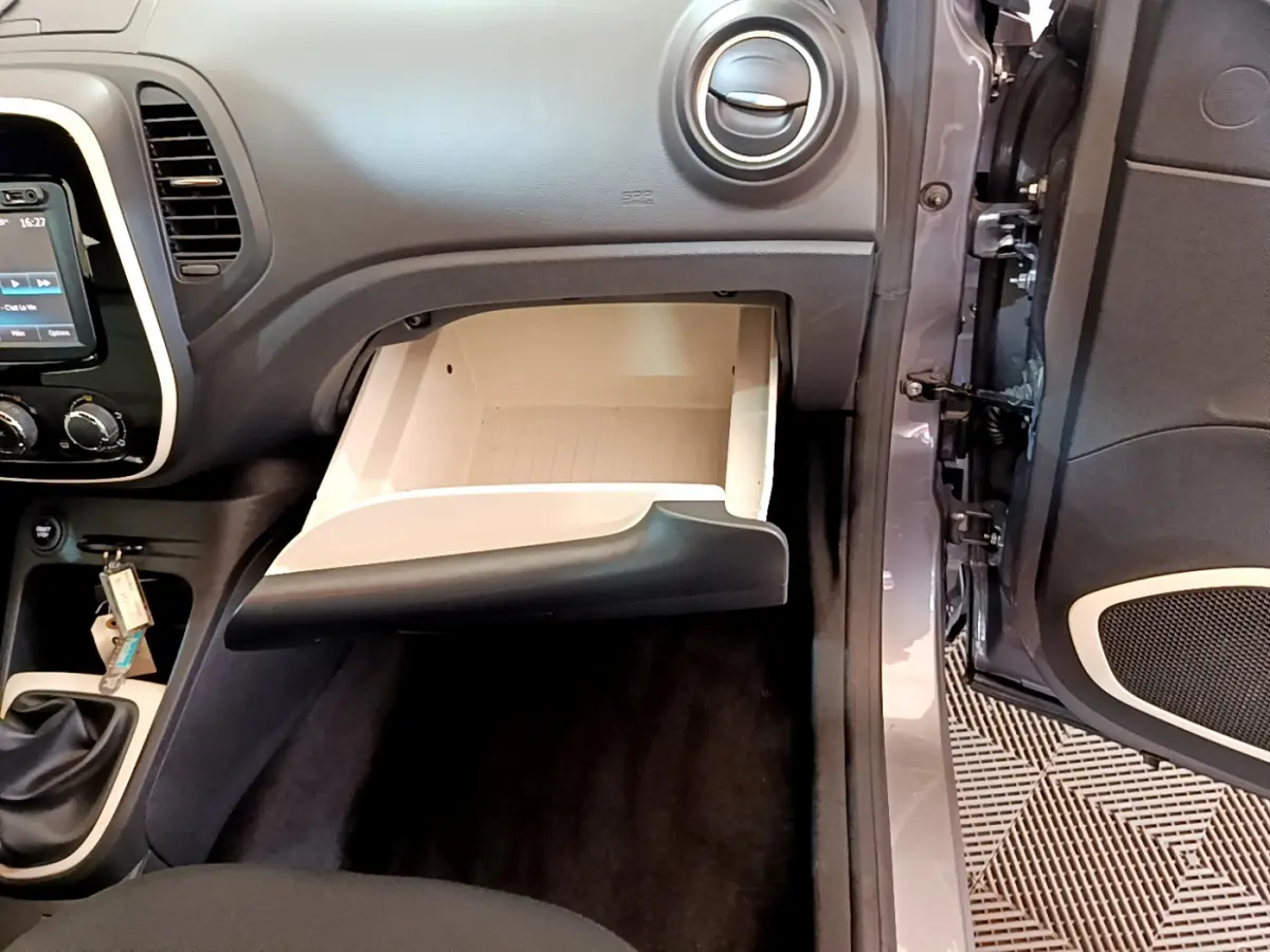 Intérieur Renault Captur Business gris foncé, vue côté passager sur boîte à gants ouverte et console centrale avec levier de vitesses manuel.