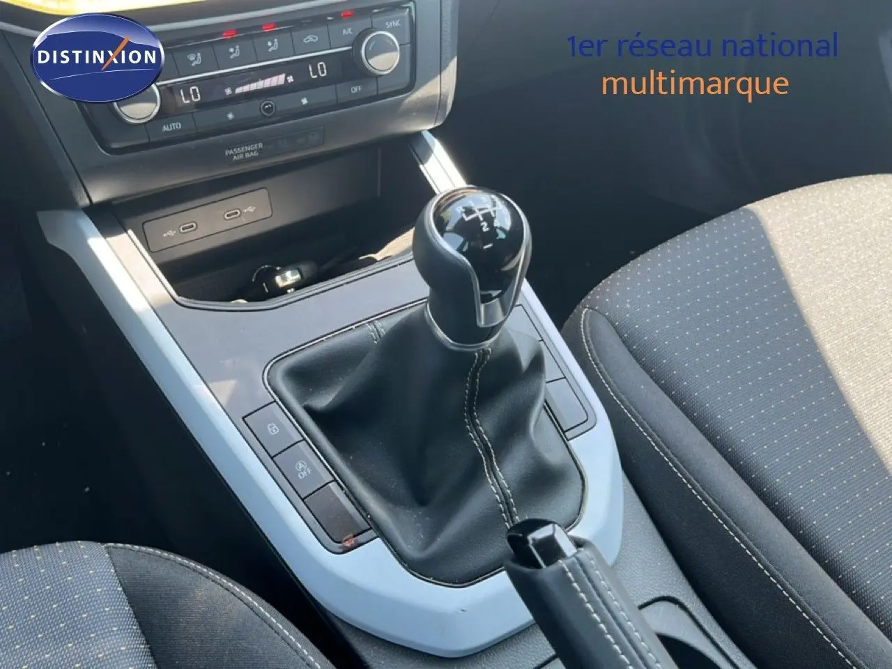 Gros plan sur la console centrale du SEAT Arona 2025, mettant en valeur le levier de vitesse manuel et les sièges tissu gris.