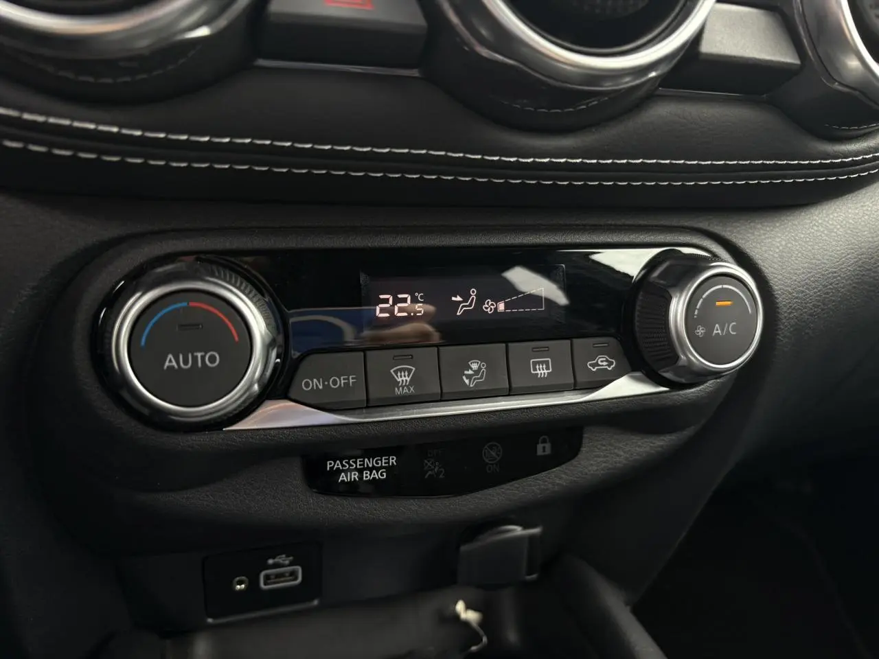 Gros plan sur la commande de climatisation automatique du Nissan Juke blanc perle 2024 avec affichage digital à 22,5°C.