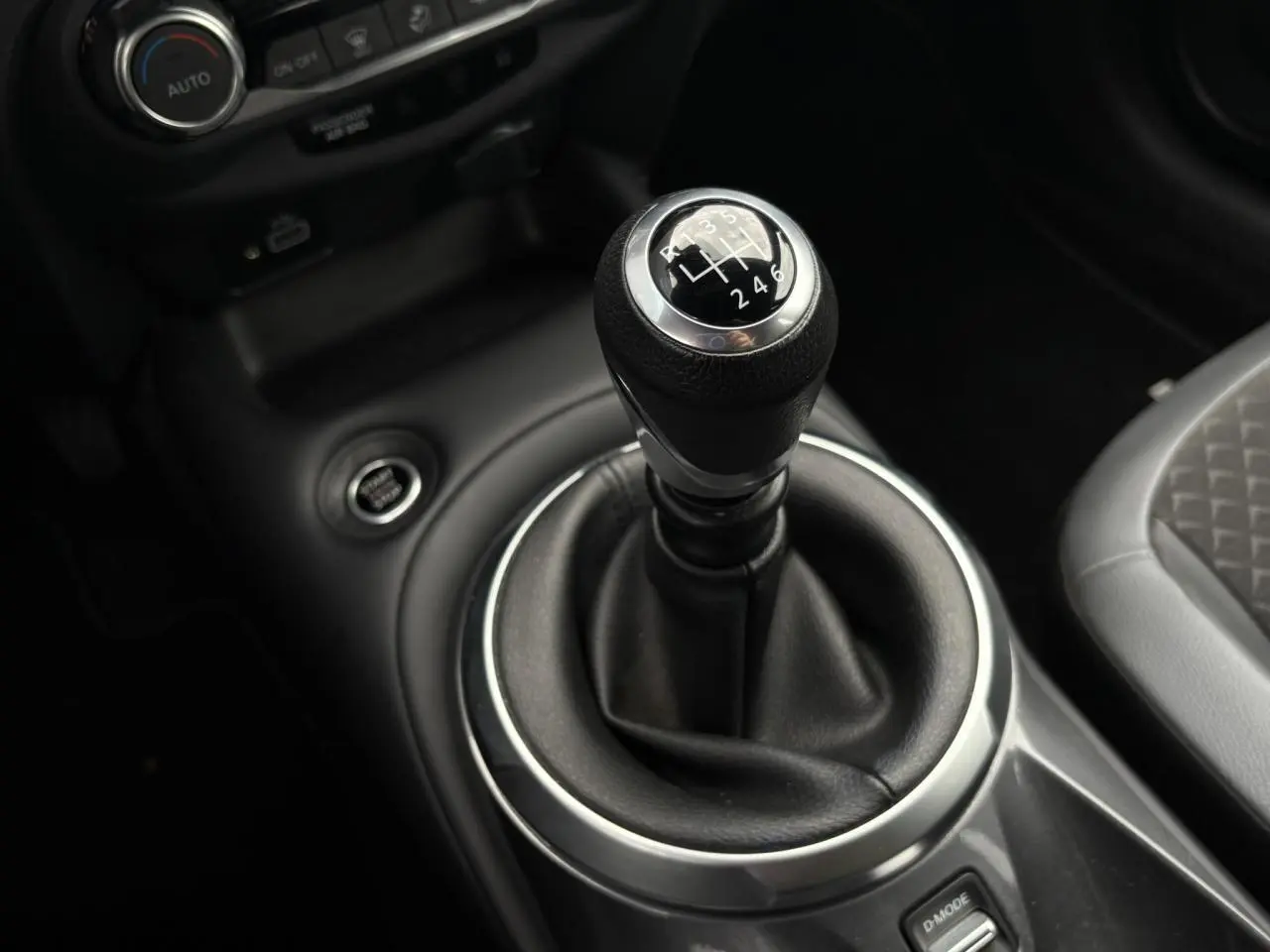 Le levier de vitesses manuel noir du Nissan Juke 2024, avec console centrale et siège partiel gris visible.