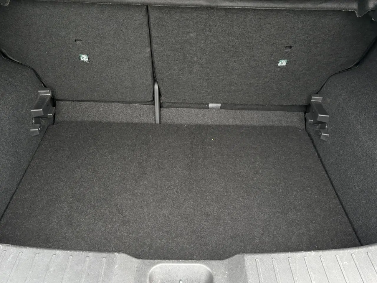 Coffre spacieux et vide du Nissan Juke blanc perle 2024, vue intérieure arrière avec revêtement noir.