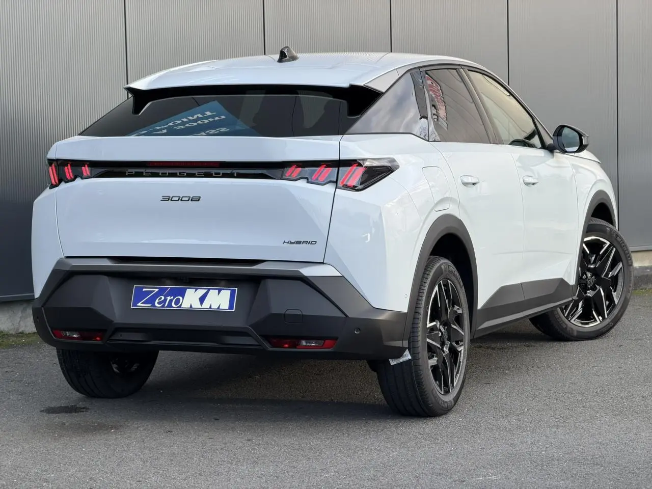 Vue 3/4 arrière droite du Peugeot 3008 Hybrid blanc Okénite avec feux arrière à LED 3 griffes et jantes alliage noires.