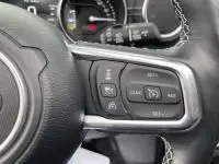 Gros plan sur les commandes au volant d'une Jeep Wrangler Unlimited 2023, avec coutures blanches visibles sur le cuir noir.