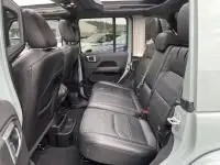 Vue intérieure arrière montrant les sièges en cuir noir du Jeep Wrangler Unlimited 2023, version hybride rechargeable vert métal.