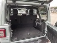 Vue arrière ouverte du Jeep Wrangler Unlimited 2023 vert métal, montrant le coffre spacieux et l'intérieur sombre.