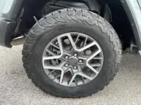 Gros plan sur la roue tout-terrain avec jante alliage du Jeep Wrangler Unlimited vert métal 2023 hybride rechargeable.