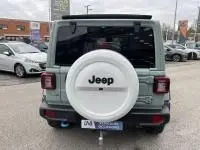 Vue arrière d'un Jeep Wrangler Unlimited 2023 vert métal avec roue de secours blanche et logo Jeep visible.
