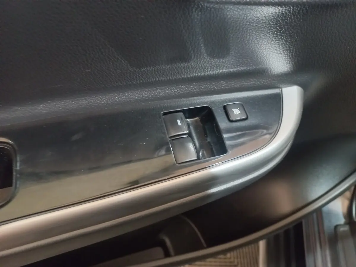 Gros plan sur les commandes de lève-vitre et verrouillage sur la porte intérieure côté conducteur du Mitsubishi L200 gris foncé.