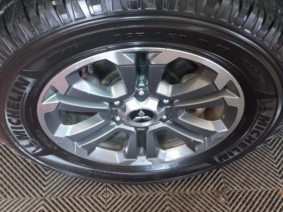 Gros plan sur la jante aluminium grise et le pneu Michelin du Mitsubishi L200 gris foncé, version 2020.