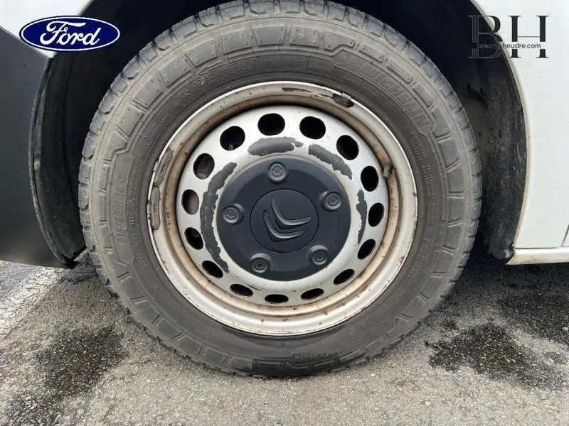 Gros plan sur la roue avant droite d'un Citroën Jumpy blanc Banquise avec jante acier et logo Citroën central.