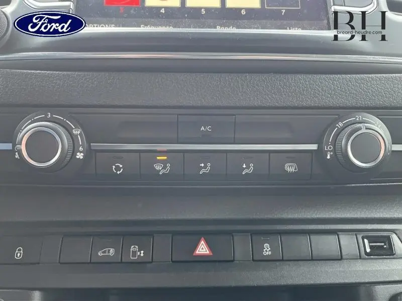 Tableau de bord du Citroën Jumpy blanc, vue rapprochée sur les commandes de climatisation et boutons fonctionnels.