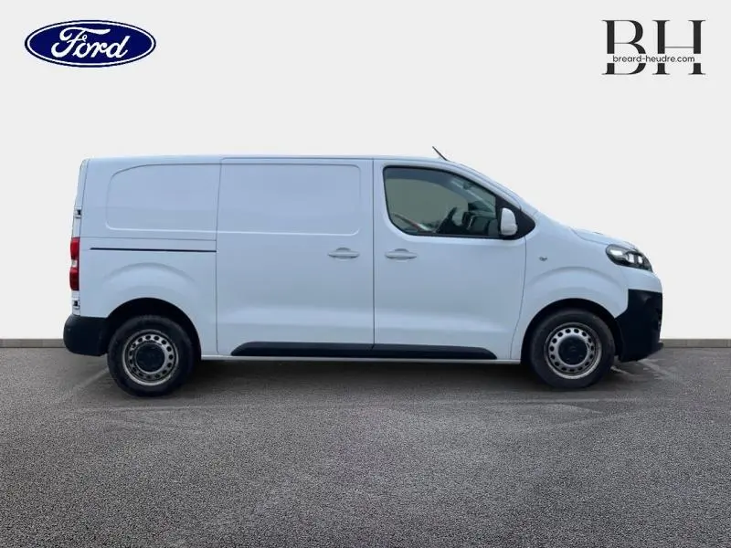 Fourgon blanc en vue de profil côté gauche, avec porte latérale coulissante et jantes acier noires.