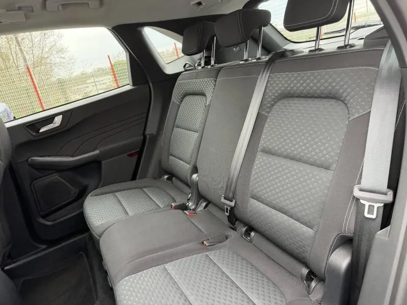 Vue intérieure du Ford Kuga 2024 montrant les sièges arrière gris avec surpiqûres et ceintures de sécurité visibles.