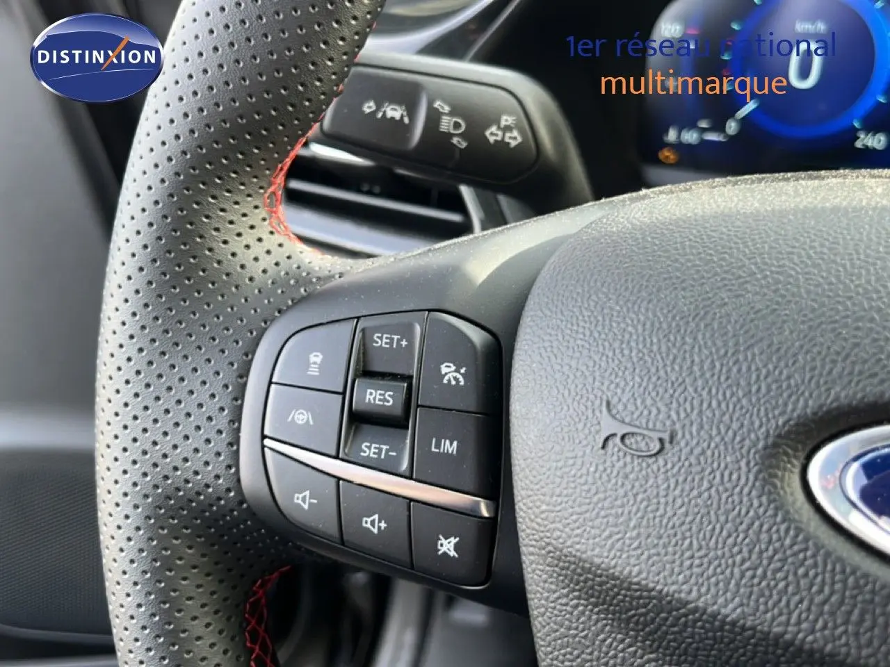 Gros plan sur le volant noir perforé avec surpiqûres rouges du Ford Puma 2023, boutons de commande visibles côté gauche.