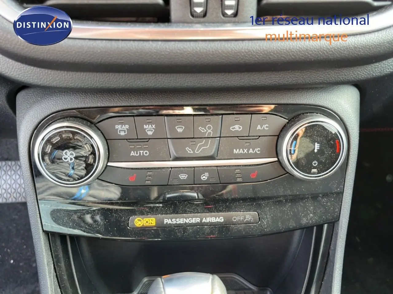 Gros plan sur la console centrale de la Ford Puma noire, montrant les commandes de climatisation et le témoin d’airbag passager.