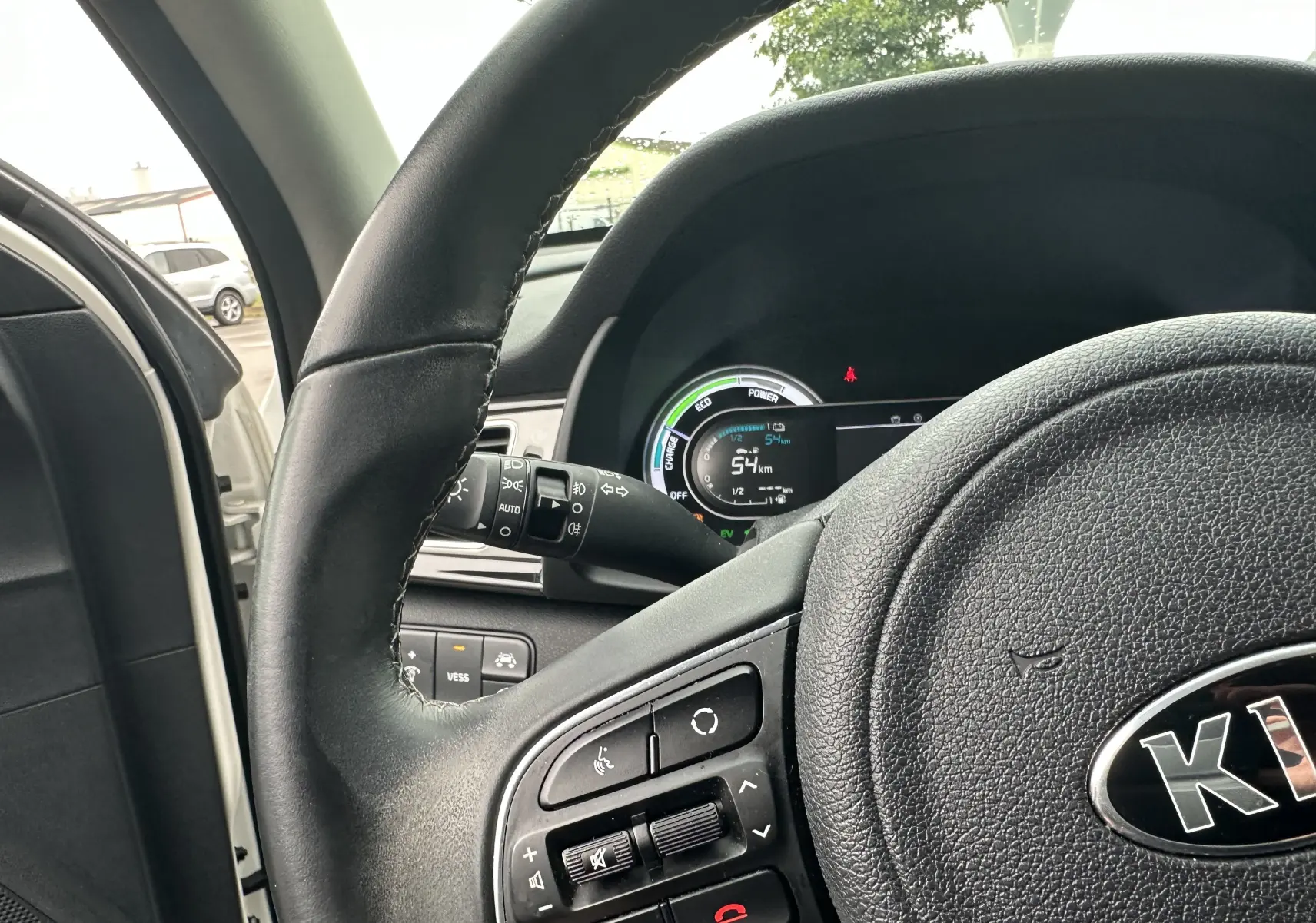 Vue rapprochée du volant et du tableau de bord digital du KIA Niro blanc céleste, affichant l'autonomie électrique.