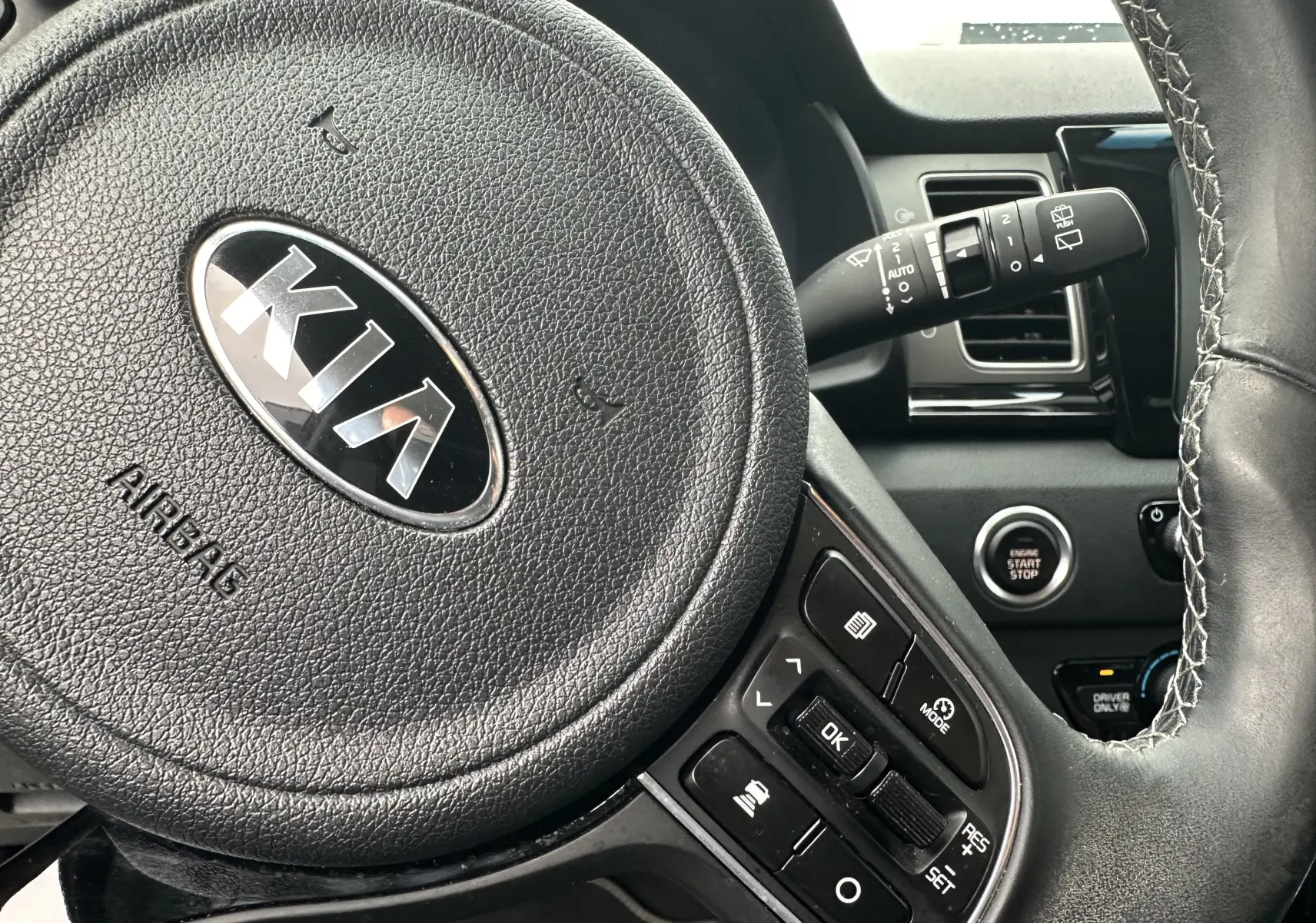 Gros plan sur le volant noir de la Kia Niro hybride rechargeable 2020 avec commandes intégrées et bouton start/stop visible.