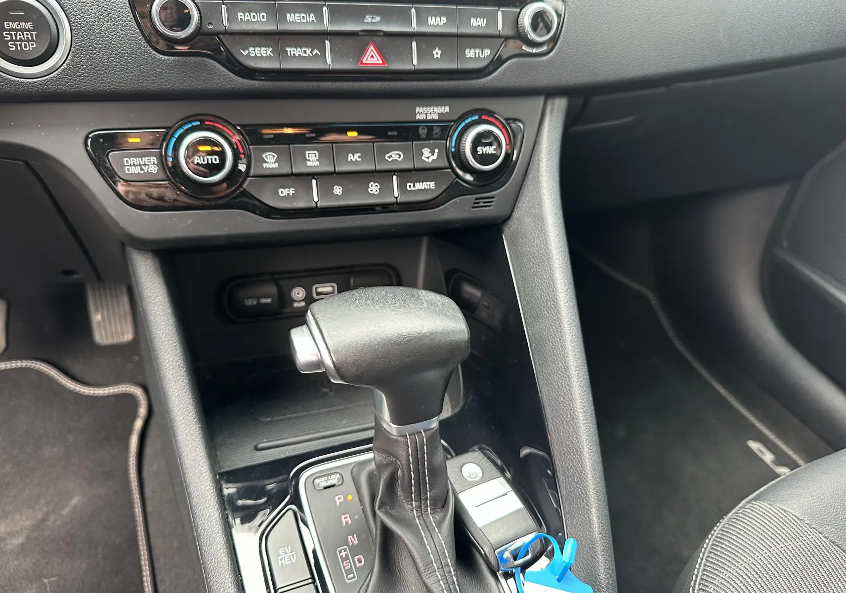 Intérieur du Kia Niro hybride rechargeable 2020, vue rapprochée sur la console centrale avec levier de vitesse automatique et commandes climatisation.