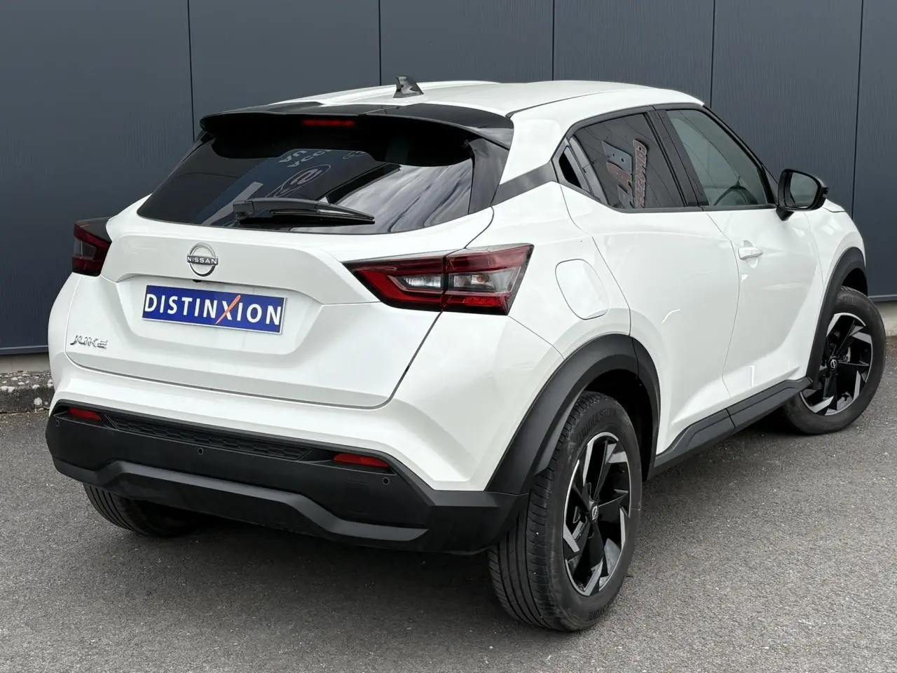 Vue 3/4 arrière droit du Nissan Juke blanc perle avec jantes alliage noires et vitres teintées.