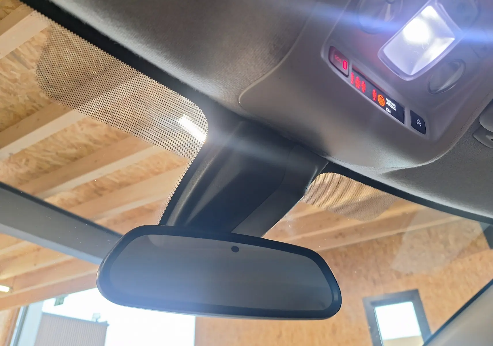 Gros plan sur le rétroviseur intérieur et plafonnier éclairé d'une Citroën C3 gris 2019 dans un garage.