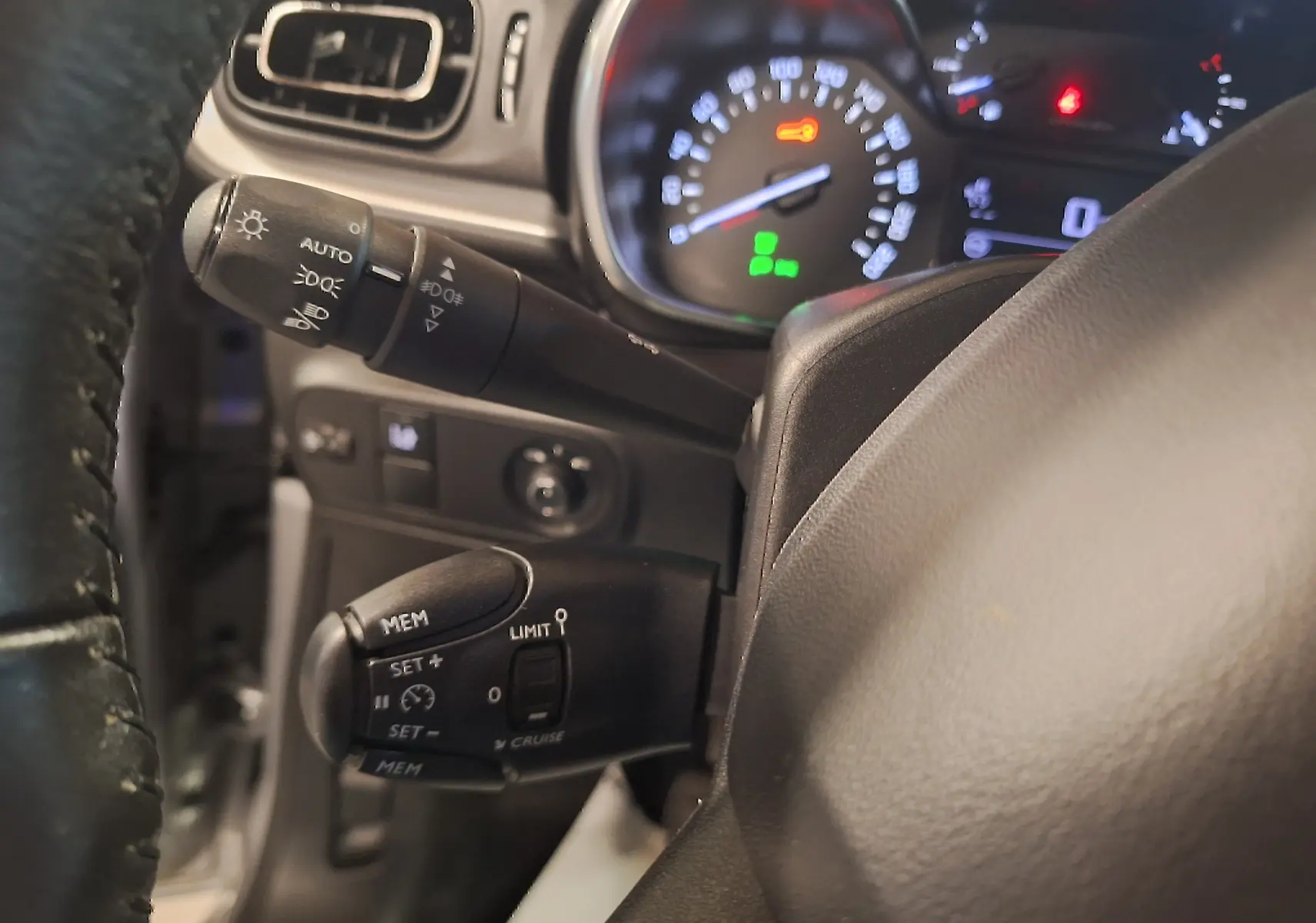 Gros plan sur le volant cuir et les commandes de régulateur de vitesse du tableau de bord d'une Citroën C3 gris 2019.