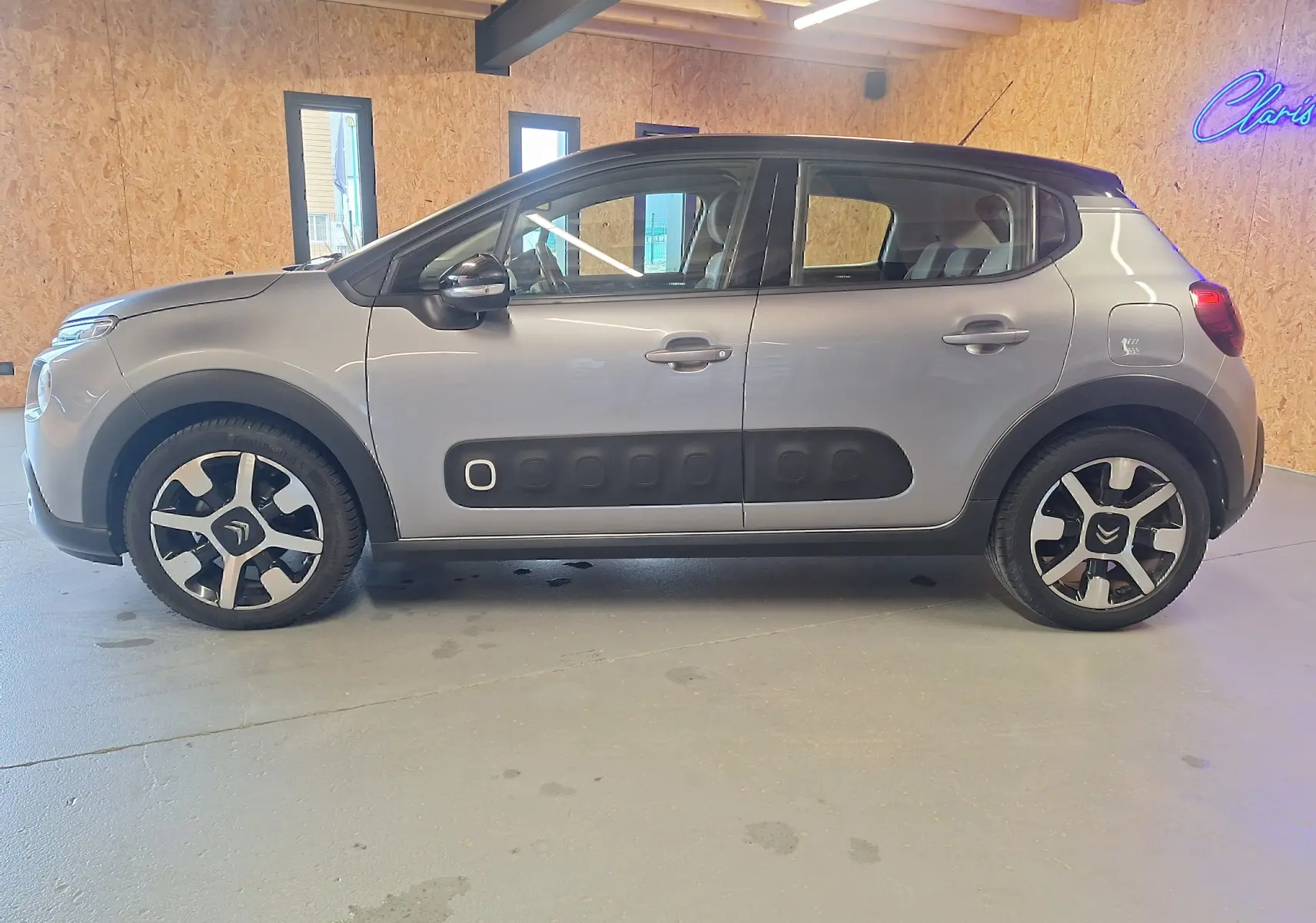 Profil côté gauche d'une Citroën C3 gris avec protections latérales noires et jantes alliage au design distinctif.