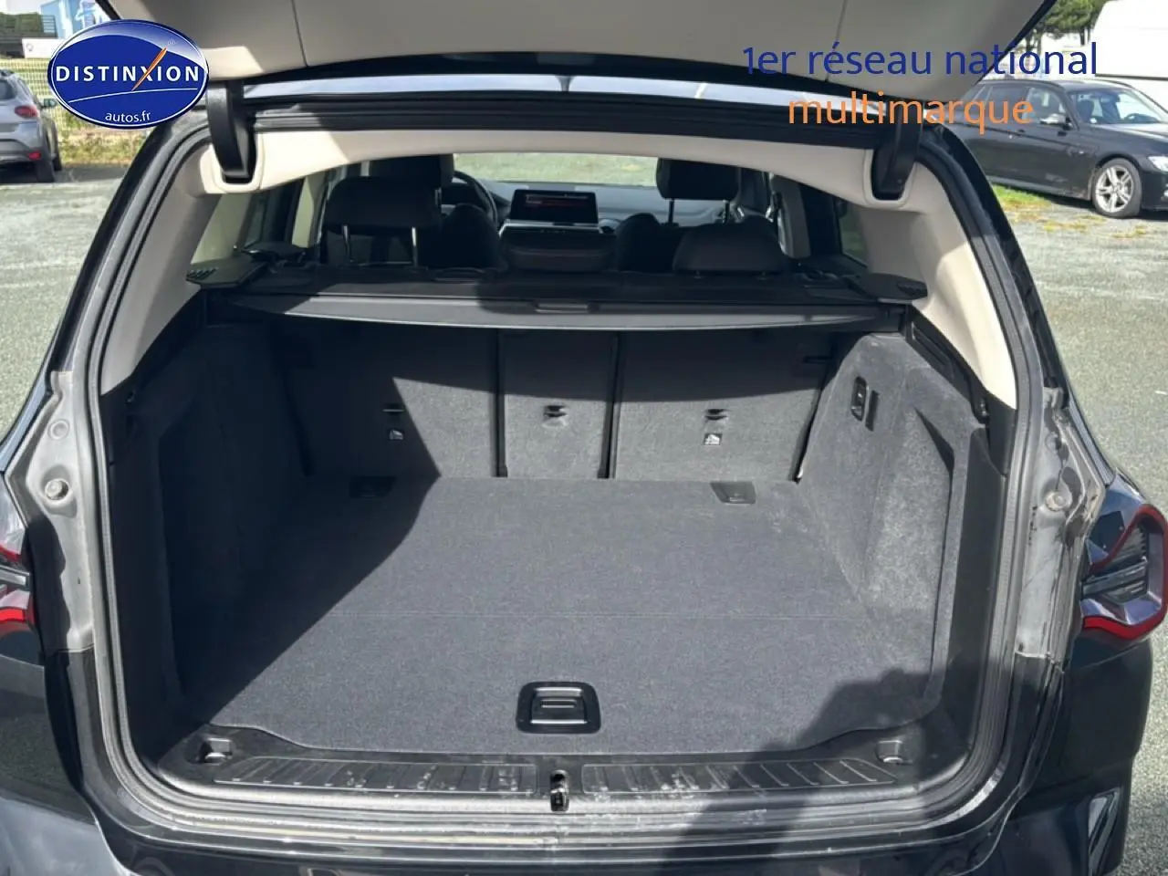 Coffre ouvert d’un BMW X3 noir (2024) vu de l’arrière, montrant l’espace de chargement et la tablette cache-bagages.