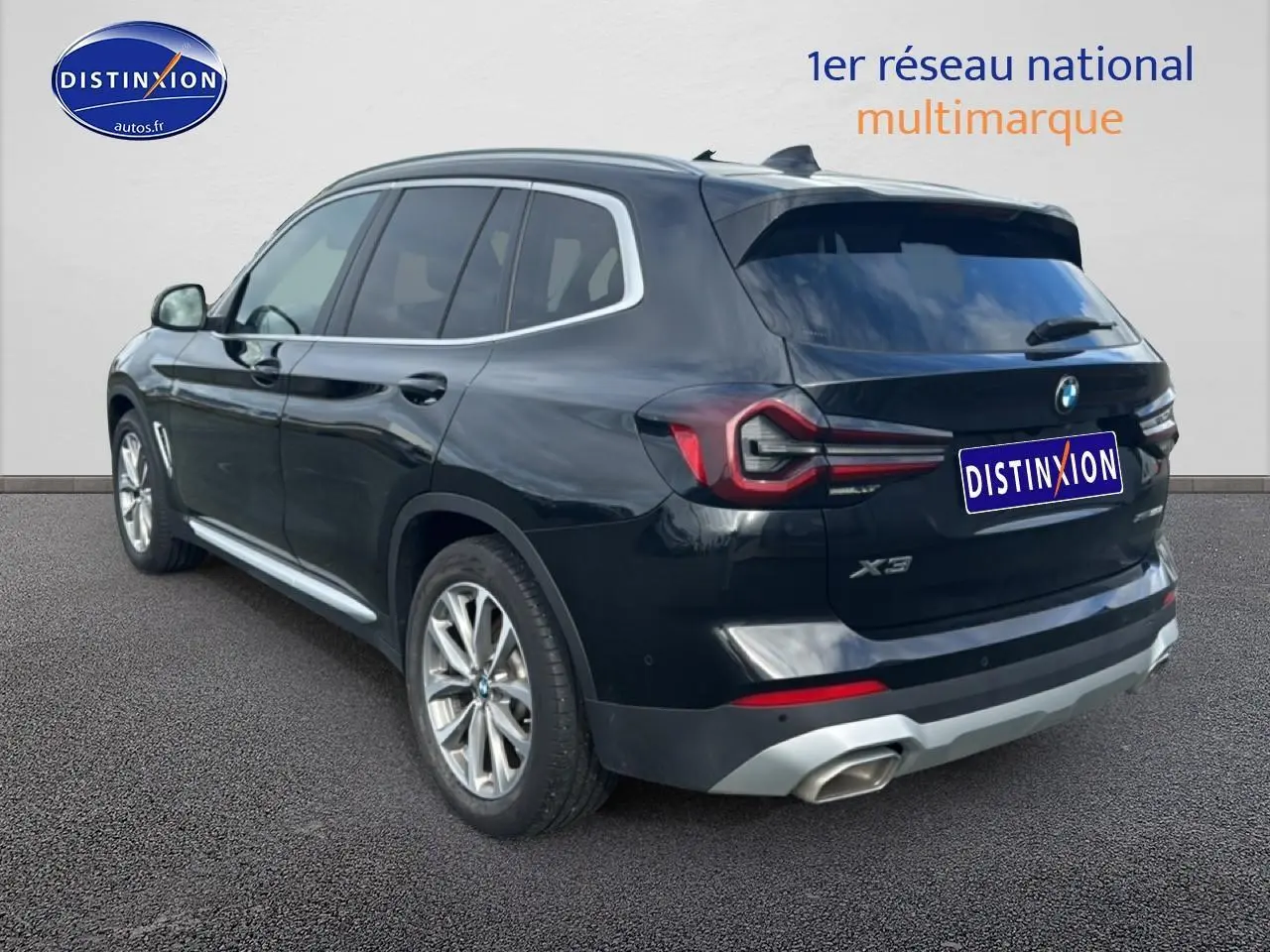 Vue 3/4 arrière droite d'un BMW X3 noir 2024 avec jantes alu et échappement double chromé.