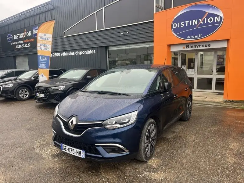 Renault Grand Scenic bleu Cosmos en 3/4 avant droit devant un concessionnaire Distinxion, avec jantes alu et phares LED.