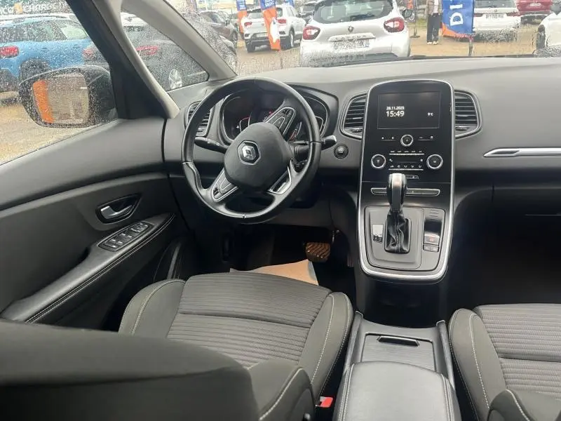 Vue intérieure avant du Renault Grand Scenic 2022, montrant le volant, tableau de bord et console centrale noire.