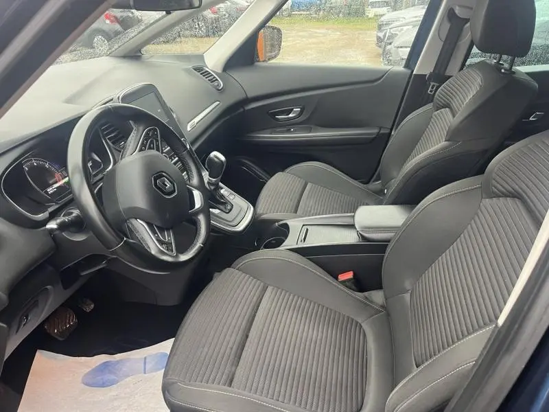 Intérieur côté conducteur du Renault Grand Scenic bleu Cosmos 2022, avec sièges tissu carbone foncé et console centrale visible.