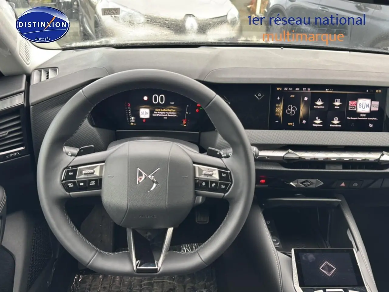 Vue intérieure centrée sur le volant cuir et le tableau de bord numérique du DS4 gris platinium 2024 hybride.