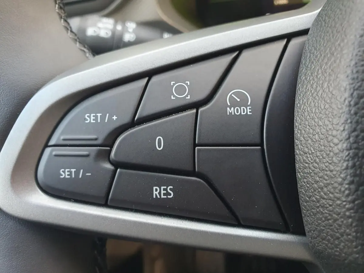 Gros plan sur les commandes au volant du Dacia Duster 2026, finition Journey, avec boutons de régulateur de vitesse.