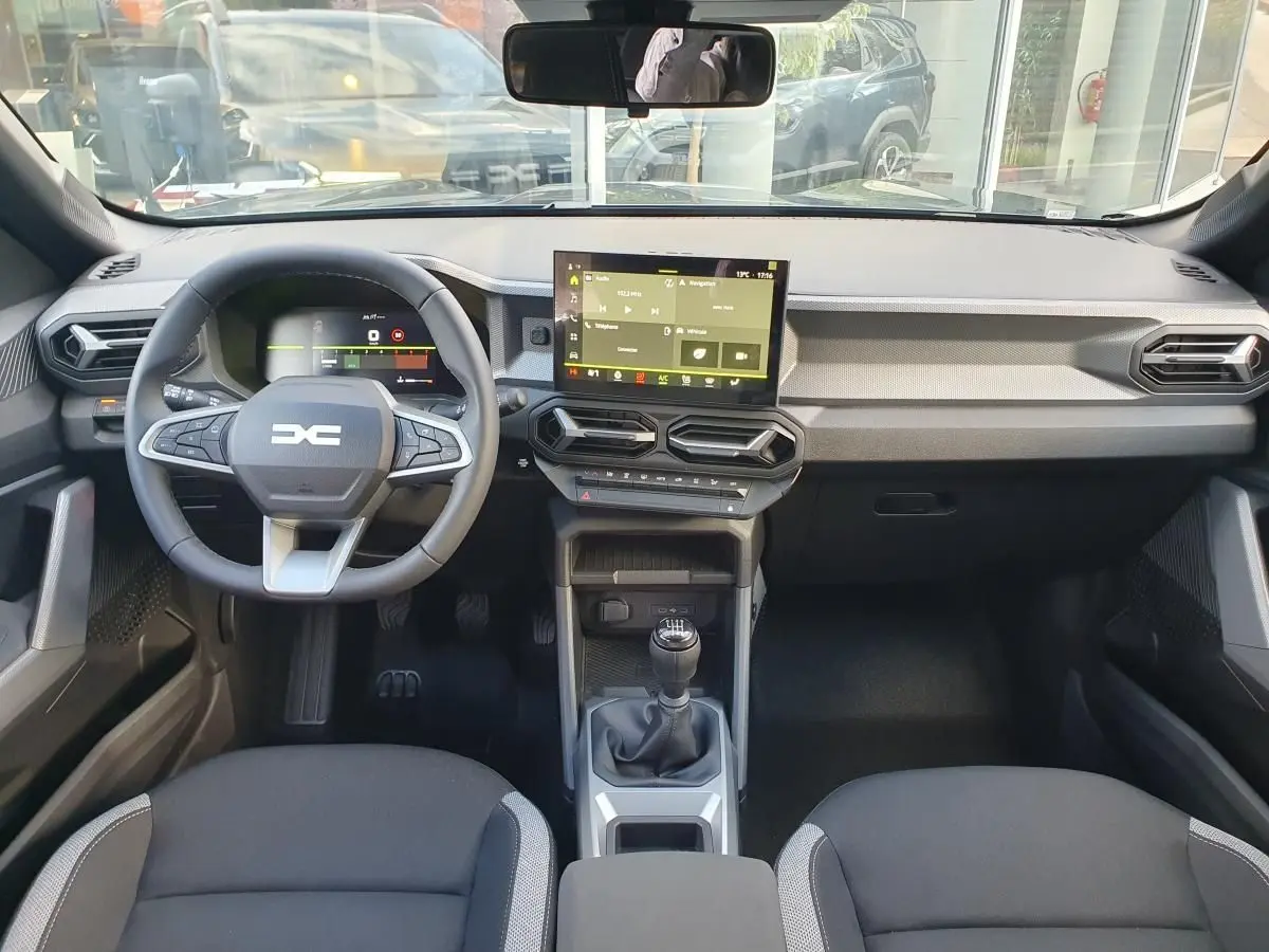 Vue intérieure avant du Dacia Duster 2026 avec tableau de bord moderne, écran tactile et volant multifonction.