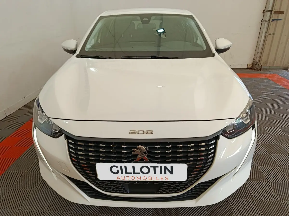 Vue avant d'une Peugeot 208 blanche, mettant en valeur sa calandre noire et ses phares LED distinctifs.