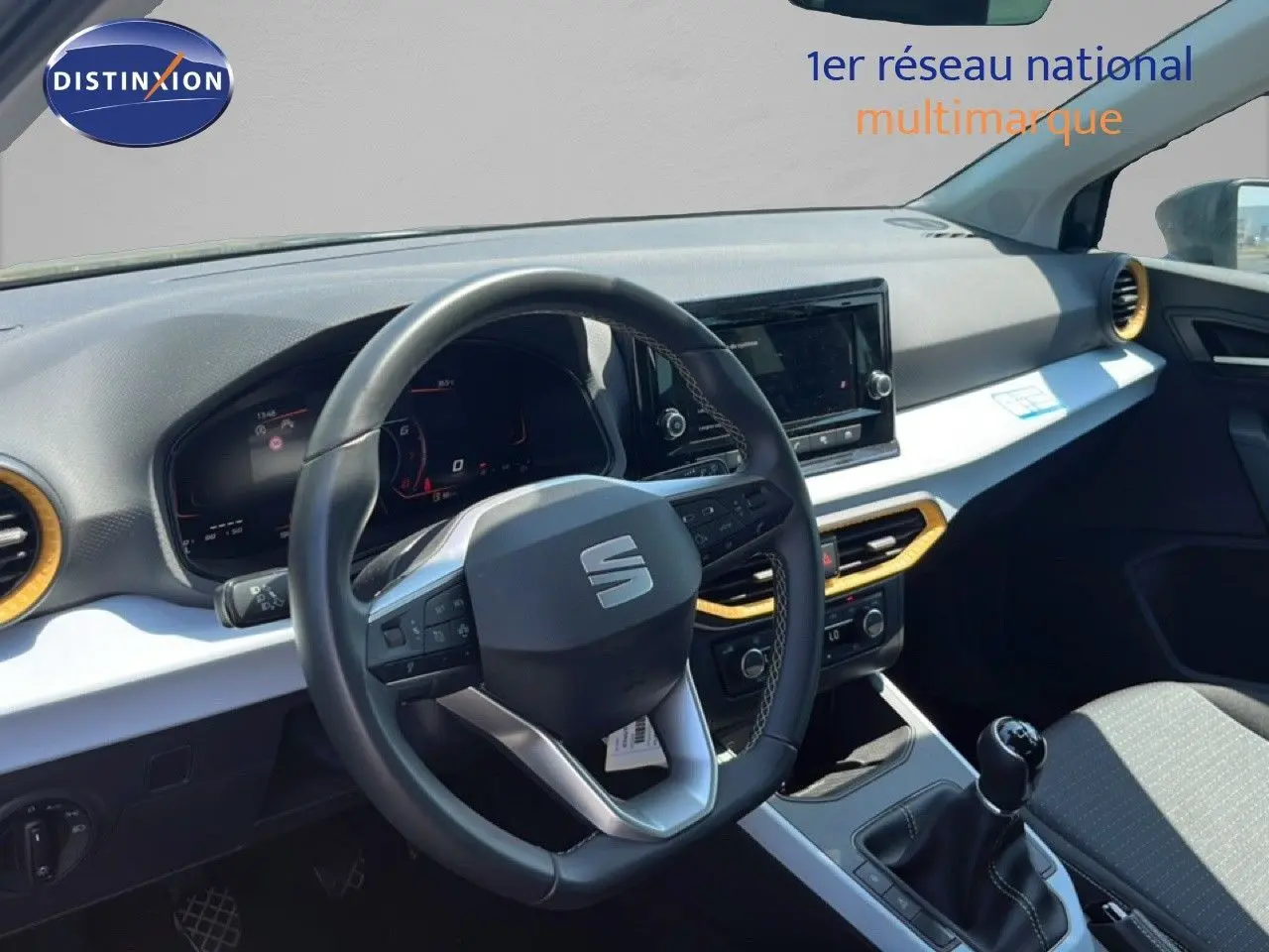 Vue intérieure du poste de conduite du SEAT Arona 2025, volant multifonction, tableau de bord numérique et levier de vitesse manuel.