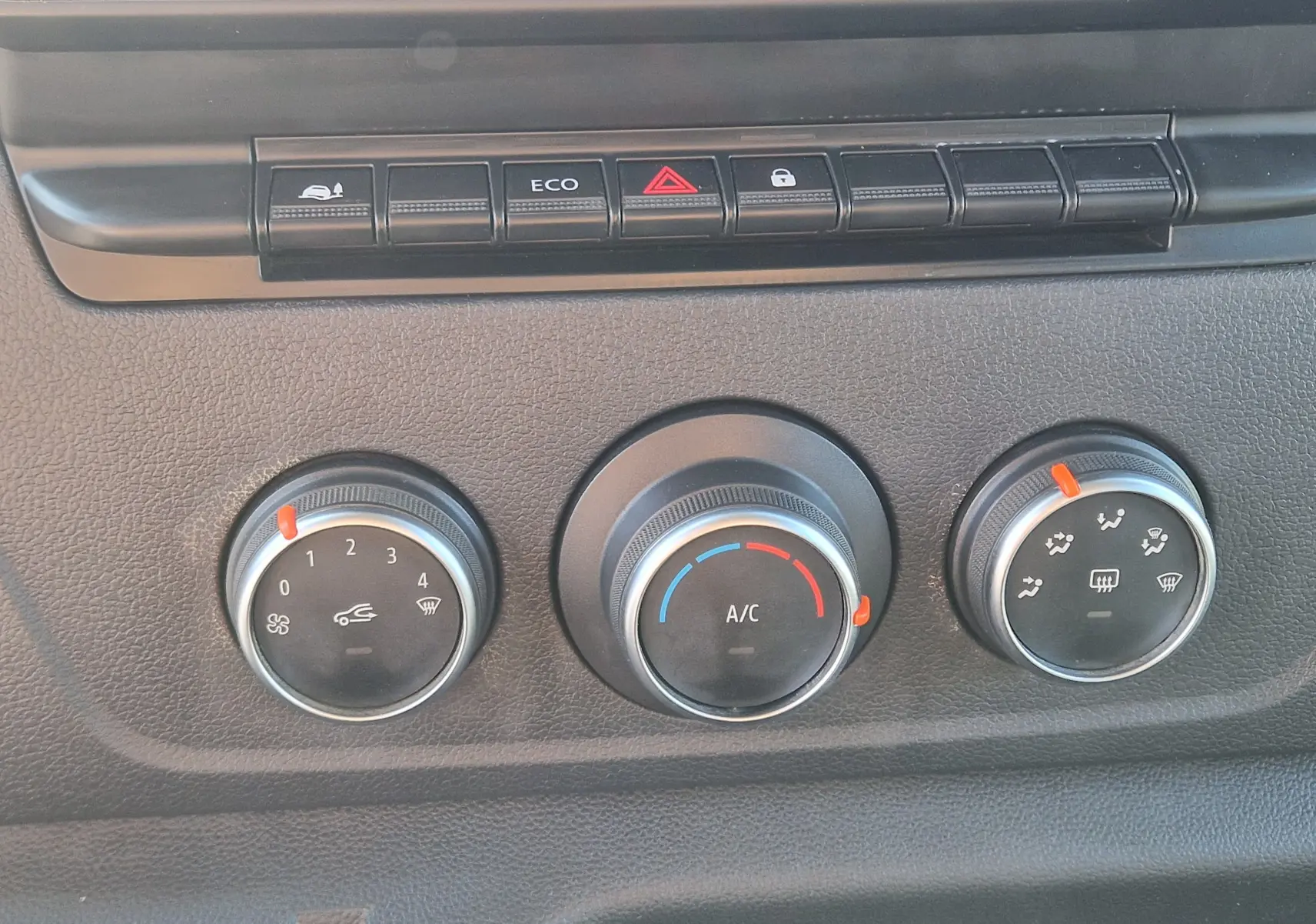 Gros plan sur les commandes de climatisation et boutons de fonction du tableau de bord du Renault Master blanc.