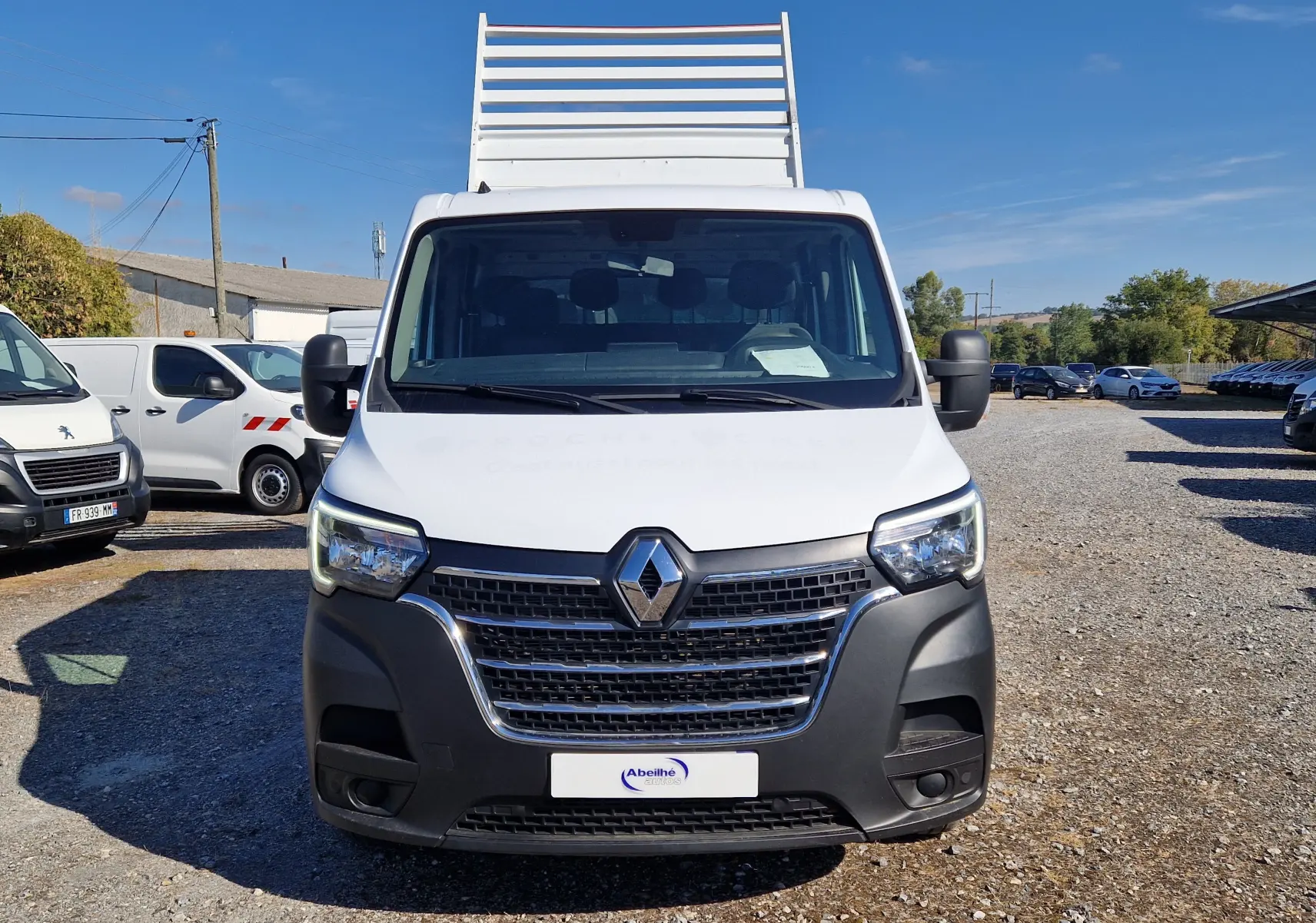 Vue avant d'un Renault Master Châssis double cabine blanc avec benne et coffre, sur un parking en extérieur.