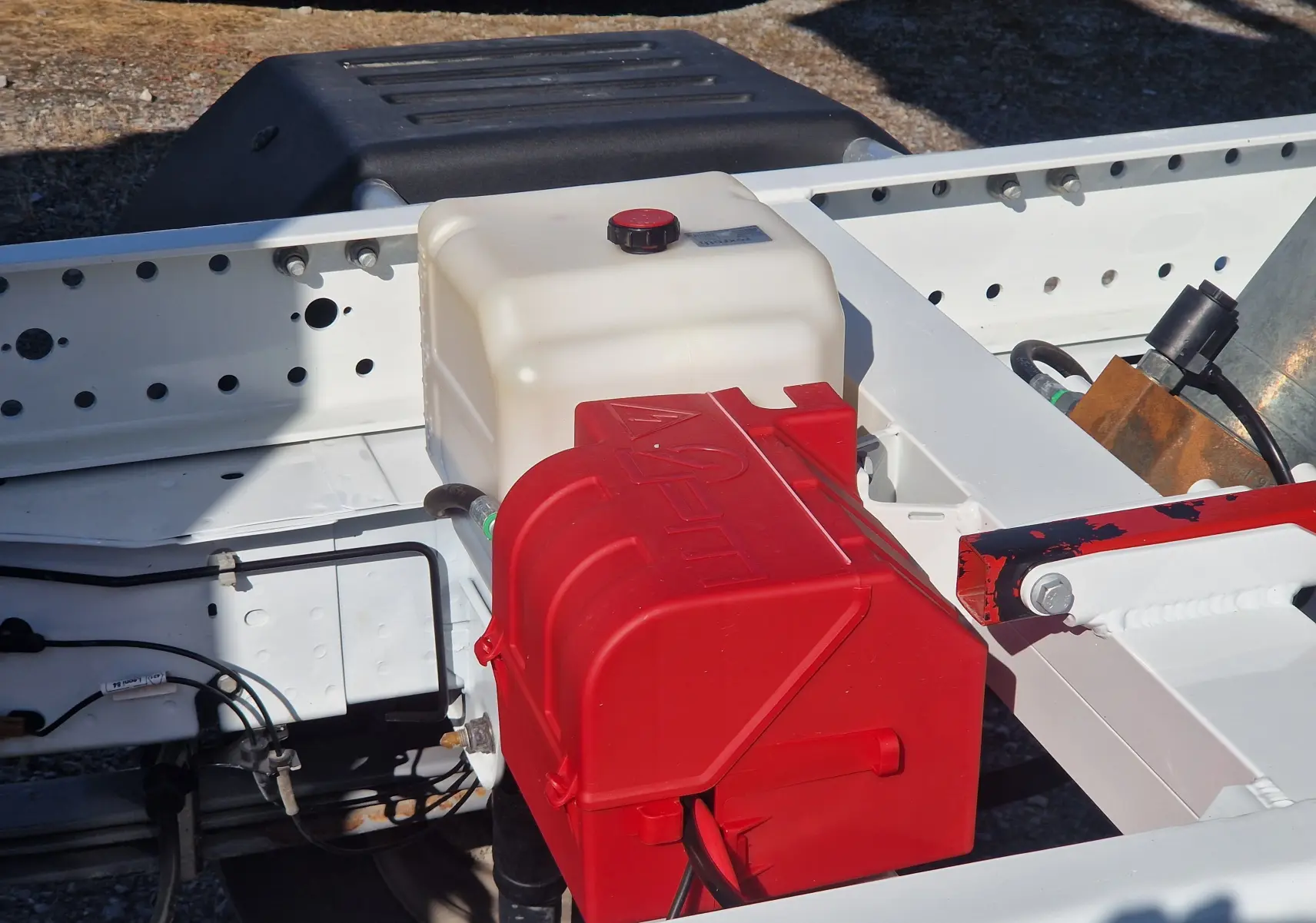 Gros plan sur le châssis blanc du Renault Master avec un réservoir blanc et une boîte rouge visible en extérieur.