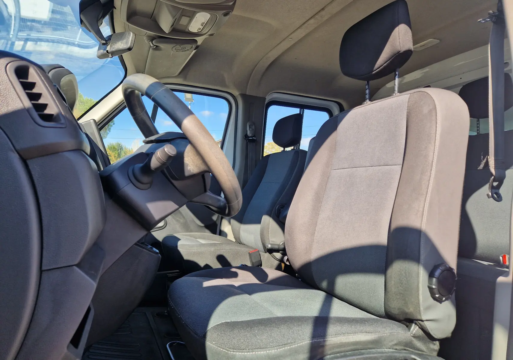 Vue intérieure côté conducteur du Renault Master Châssis Double Cabine 2022, sièges tissu gris et volant noir.