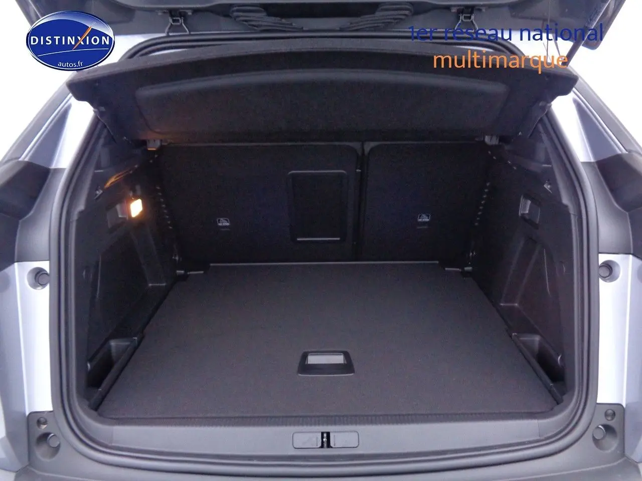 Coffre ouvert vu de l'arrière d'un Peugeot 3008 gris Artense métal, montrant un espace de chargement propre et spacieux.